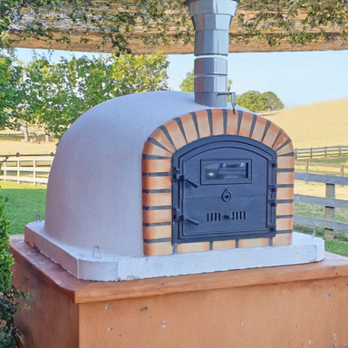 Authentic Lisboa Premium Pizza Oven outdoors with closed cast iron door and rustic brick finish
